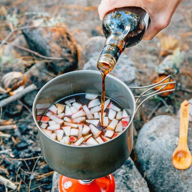 Pouring rum into a pot with apples