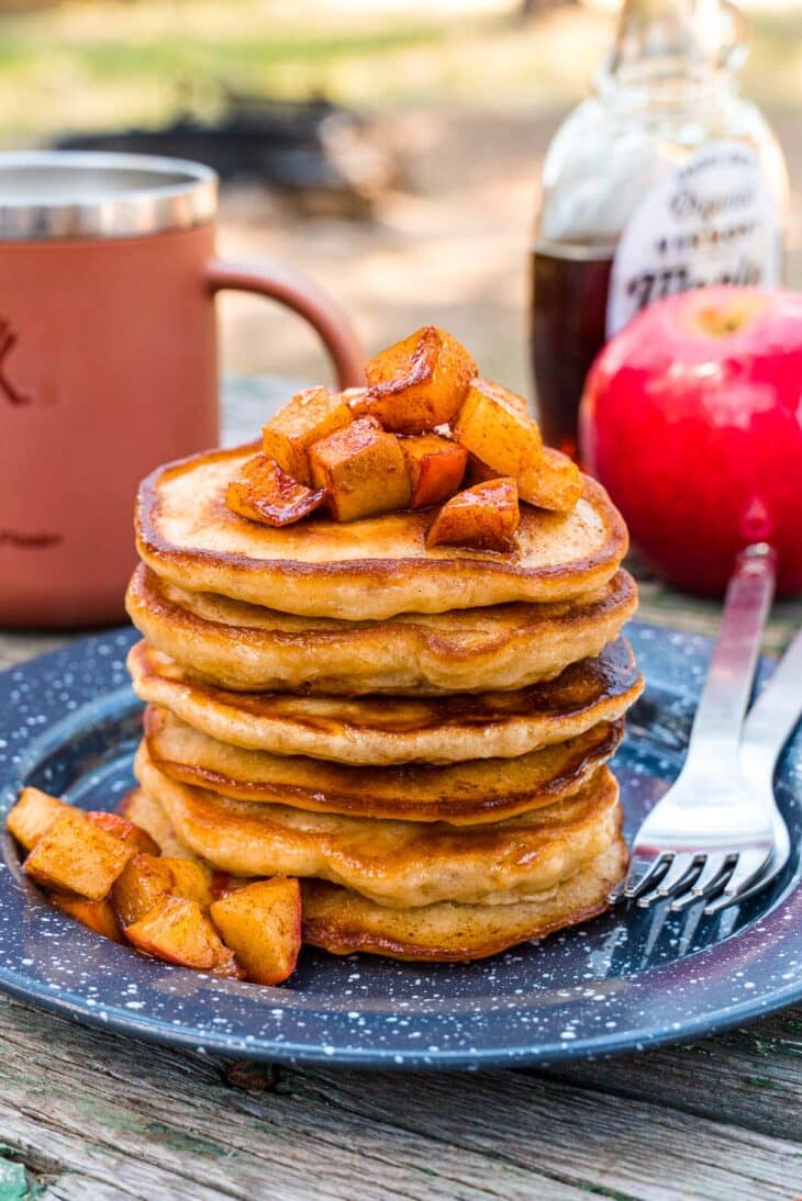 A stack of apple pancakes on a plate, topped with chopped apples.