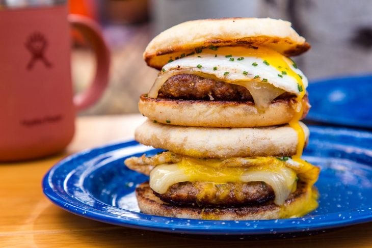 Side view of two sausage and egg sandwiches with runny yolks.