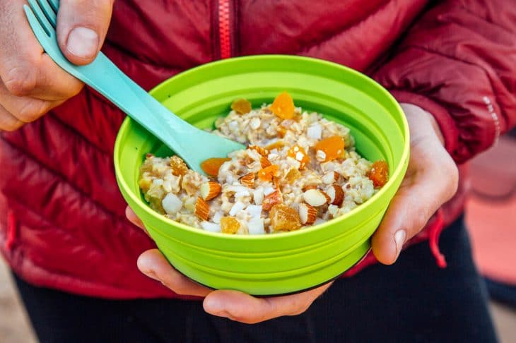 Man holding a green backpacking bowl full of apricot ginger oatmeal