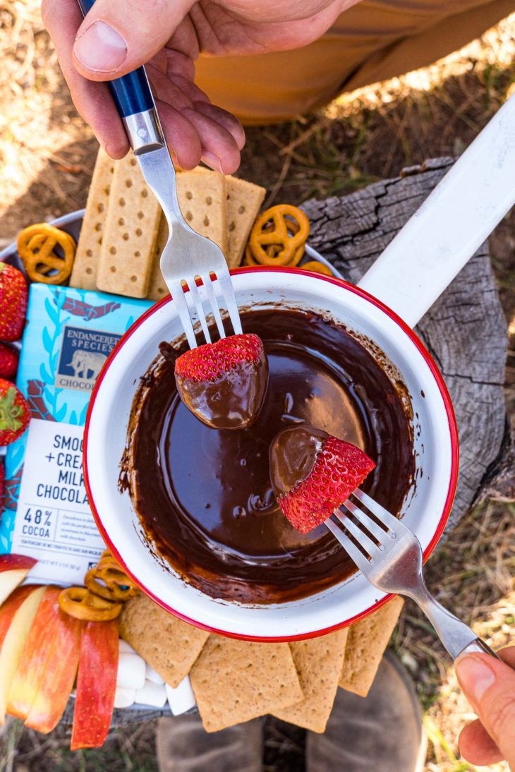 Two forks dipping strawberries into a bowl of chocolate fondue