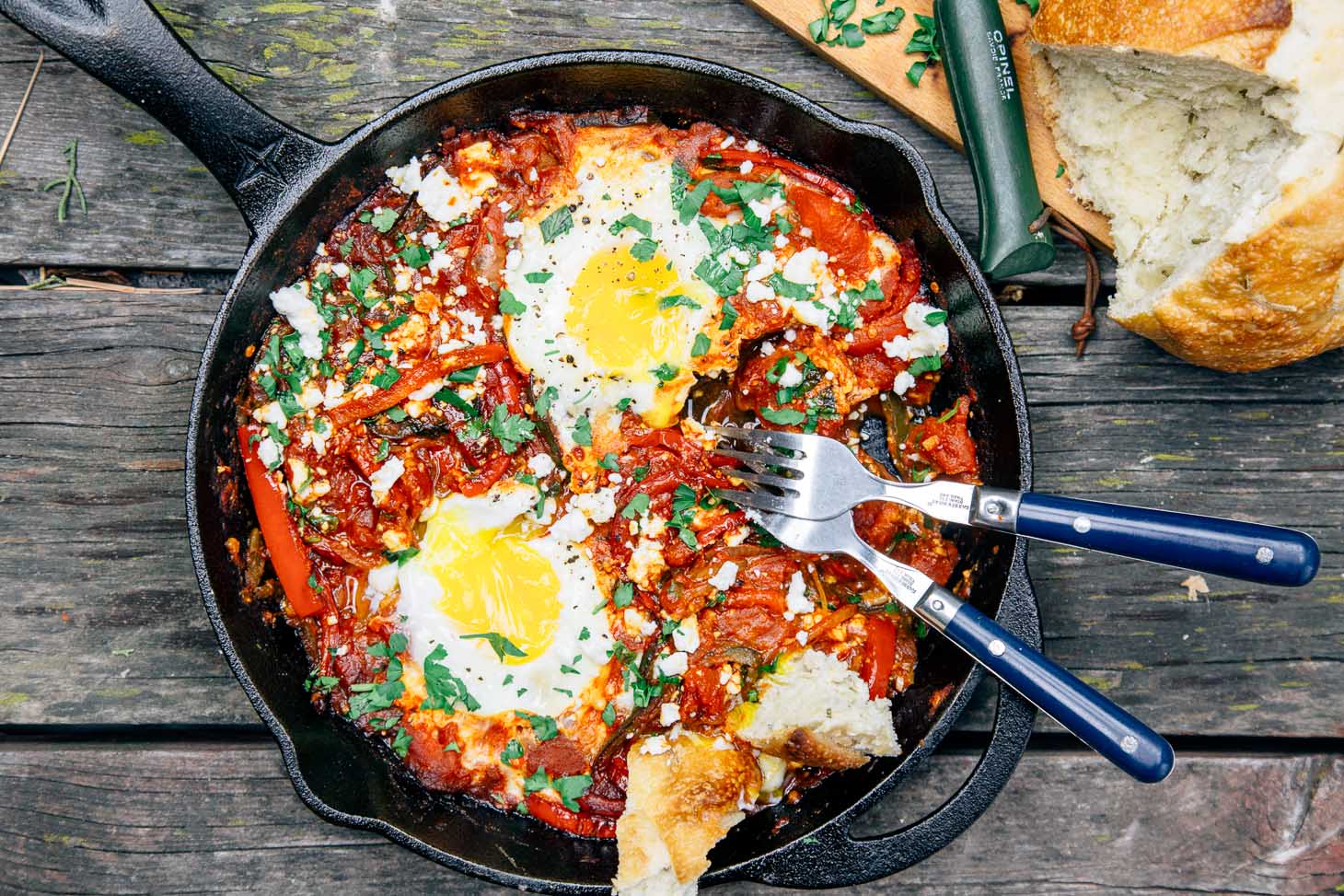 Shakshuka in a cast iron skillet with two eggs and bread