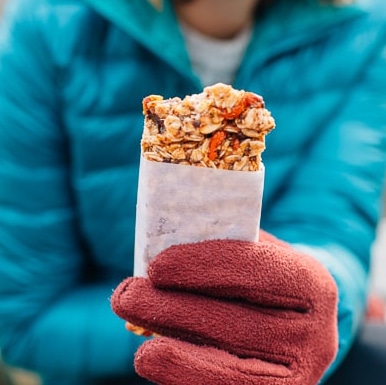 Megan holding a granola bar wrapped in white parchment paper