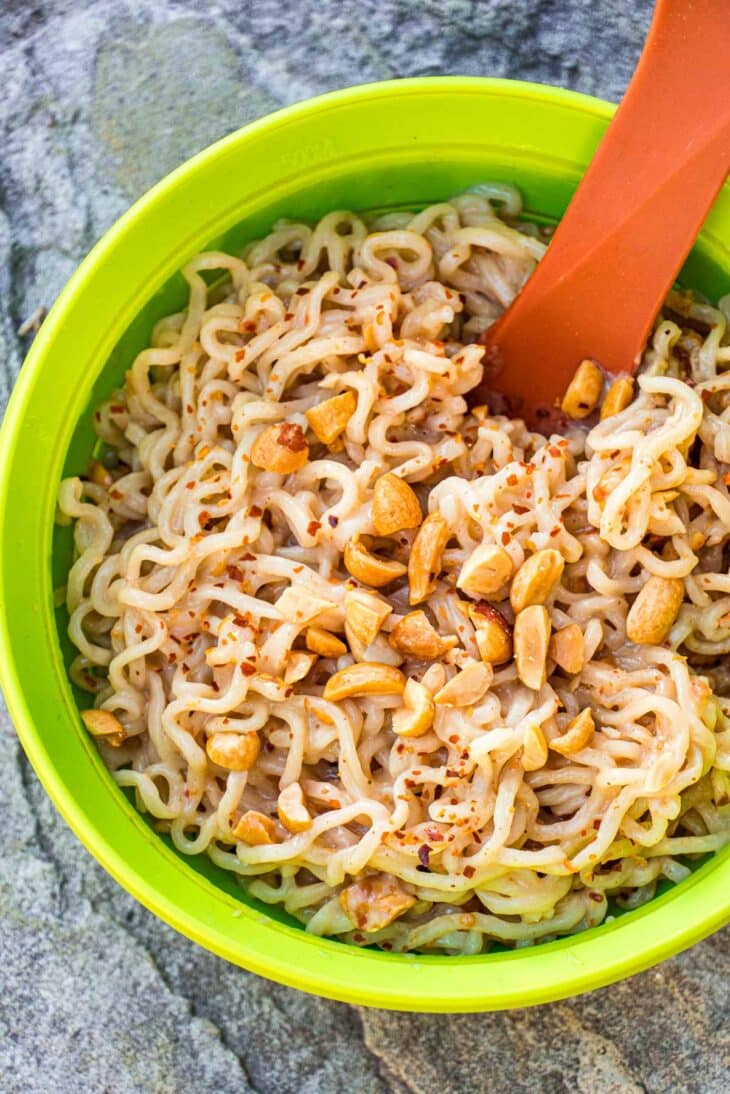 Ramen noodles with peanut sauce in a backpacking bowl on a rock.