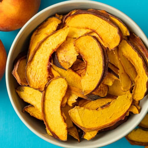 Dehydrated peaches in a bowl with a blue background