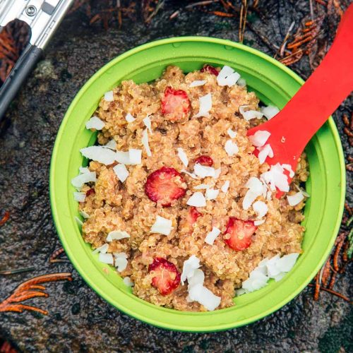 Strawberries and cream quinoa porridge in a bowl on a rock