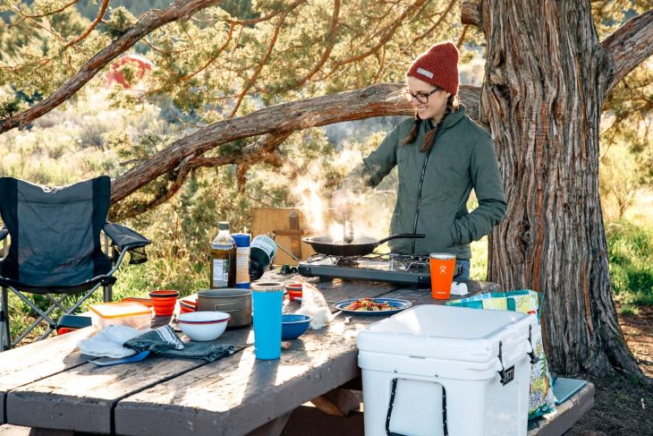 Megan cooking over a camp stove at a campsite