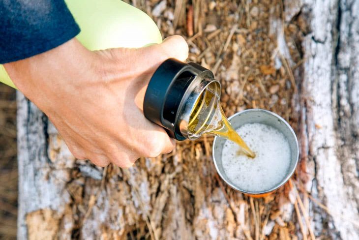 A person pouring beer from a growler into a cup