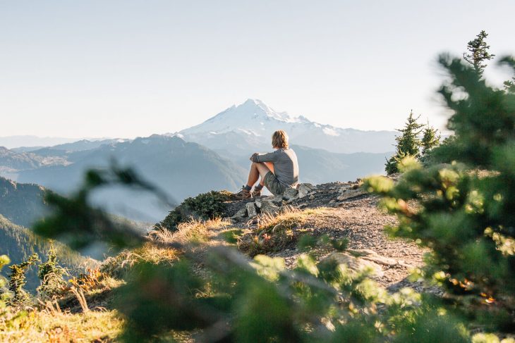 Michael sitting on an outcropping of rocks with a mountain in the distance