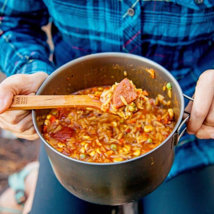 Megan holding a pot of jambalaya and scooping up a spoonful