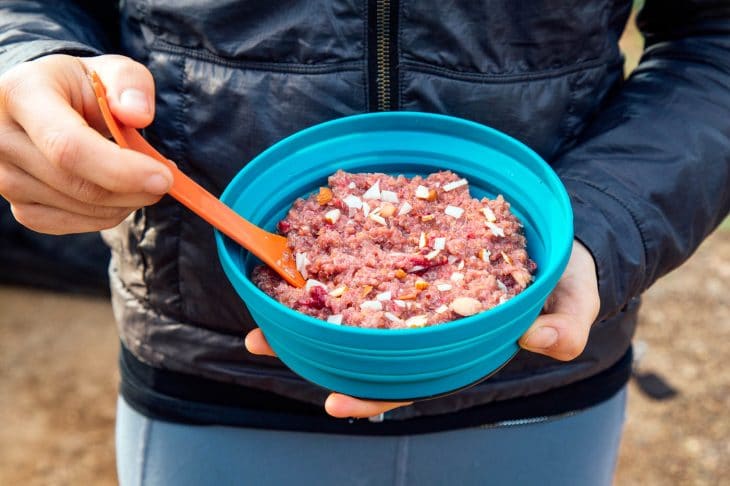 Woman holding a blue bowl full of raspberry quinoa porridge.