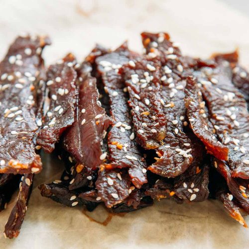 Side view of teriyaki beef jerky stacked on a napkin.