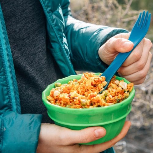 Woman holding a green bowl of Thai red curry rice