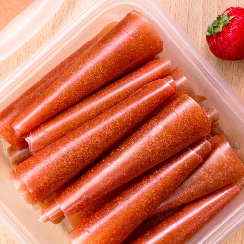 Fruit leathers rolled up and stacked in a tupperware container.