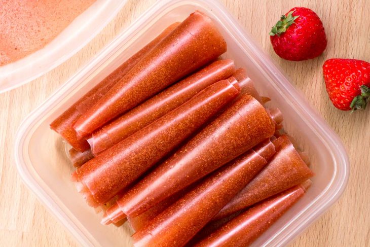 Fruit leathers rolled up and stacked in a tupperware container.